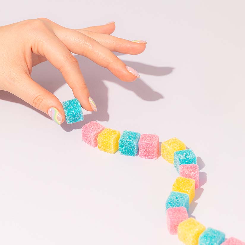 A Hand Picking Gummies from a Candy Trail